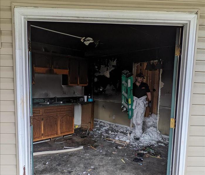 inside of a house after a fire through the back two doors, inside ash is all over the kitchen counters, SERVPRO tech inside