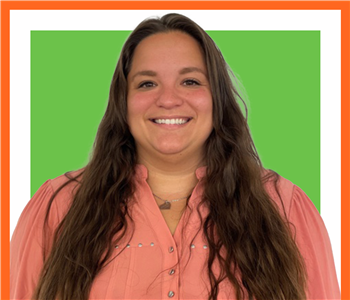 Jazmyne Higdon, female SERVPRO employee under green sign